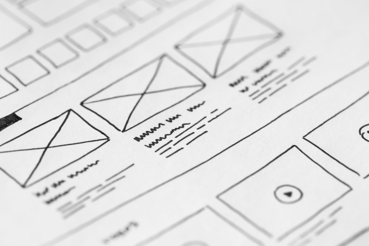 who-we-are Detailed close-up of a hand-drawn wireframe design on paper for a UX project.
